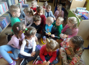 Grupa dzieci ogląda książki w bibliotece.
